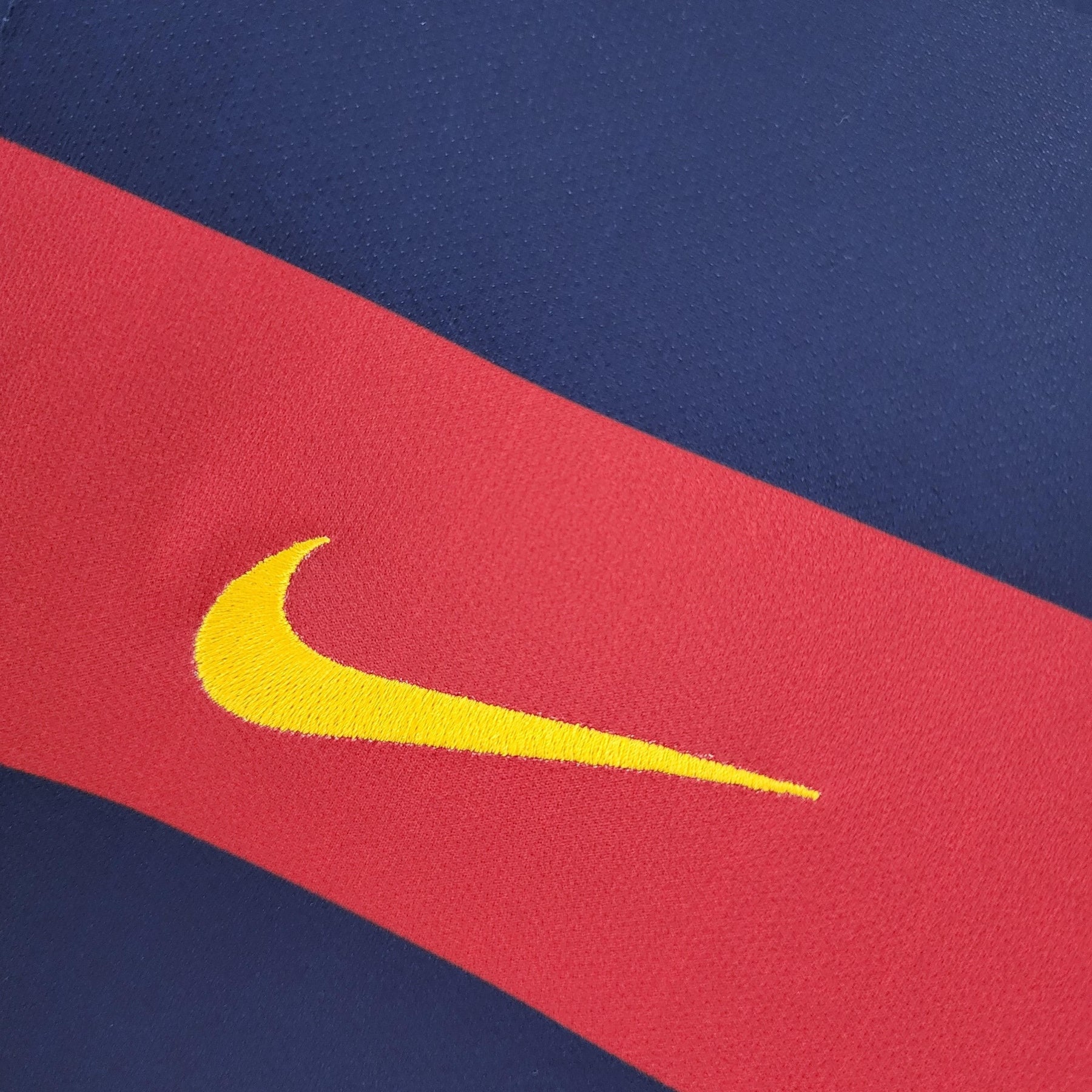 Detalhe da camisola Barcelona Home 15/16 com logo da Nike em destaque na faixa vermelha.