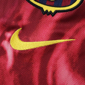 Detalhe da camisola Barcelona retro com logo da Nike em amarelo e fundo vermelho.