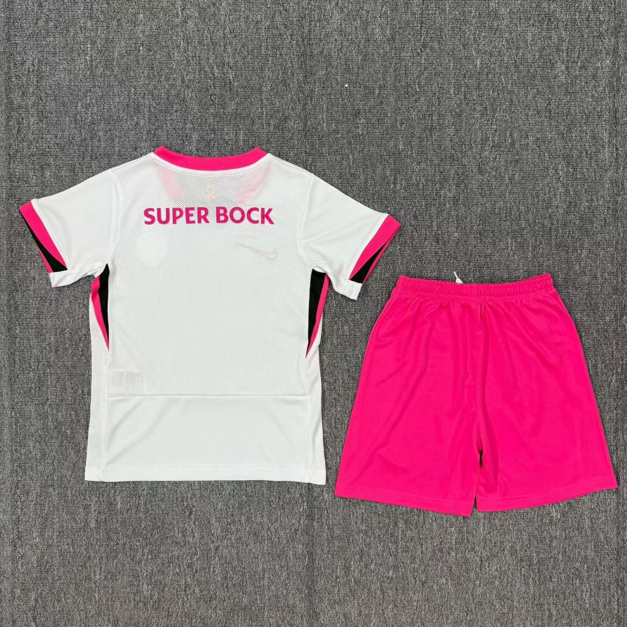 Conjunto infantil Sporting Outubro Rosa 2025/26 com camisola branca e calção pink, lançamento da OLYMPIC STORE.