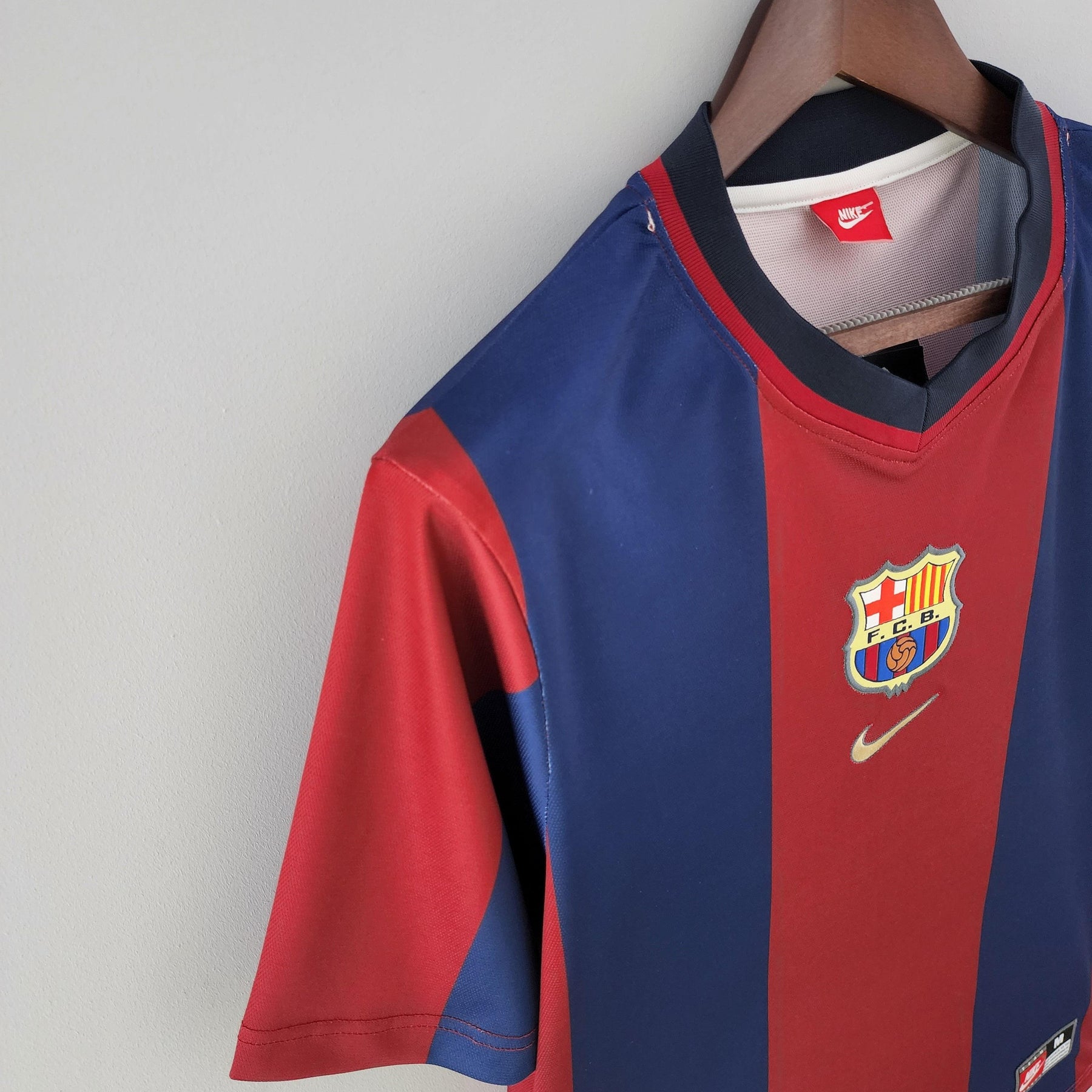 Camisa de futebol Barcelona Home 98/99 disponível na Olympic Store, em cores vermelha e azul, com escudo e logo Nike.