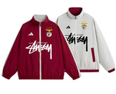 Corta-Vento Reversível Benfica 24/25 com design em duas cores, vermelho e branco, com logos do Benfica e Stüssy.