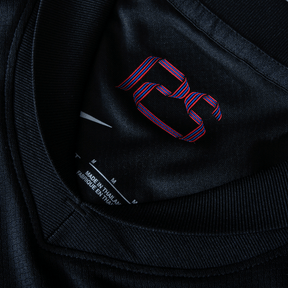 Detalhe da etiqueta interna da camisola Barcelona away 24/25 com o logotipo em vermelho e azul.