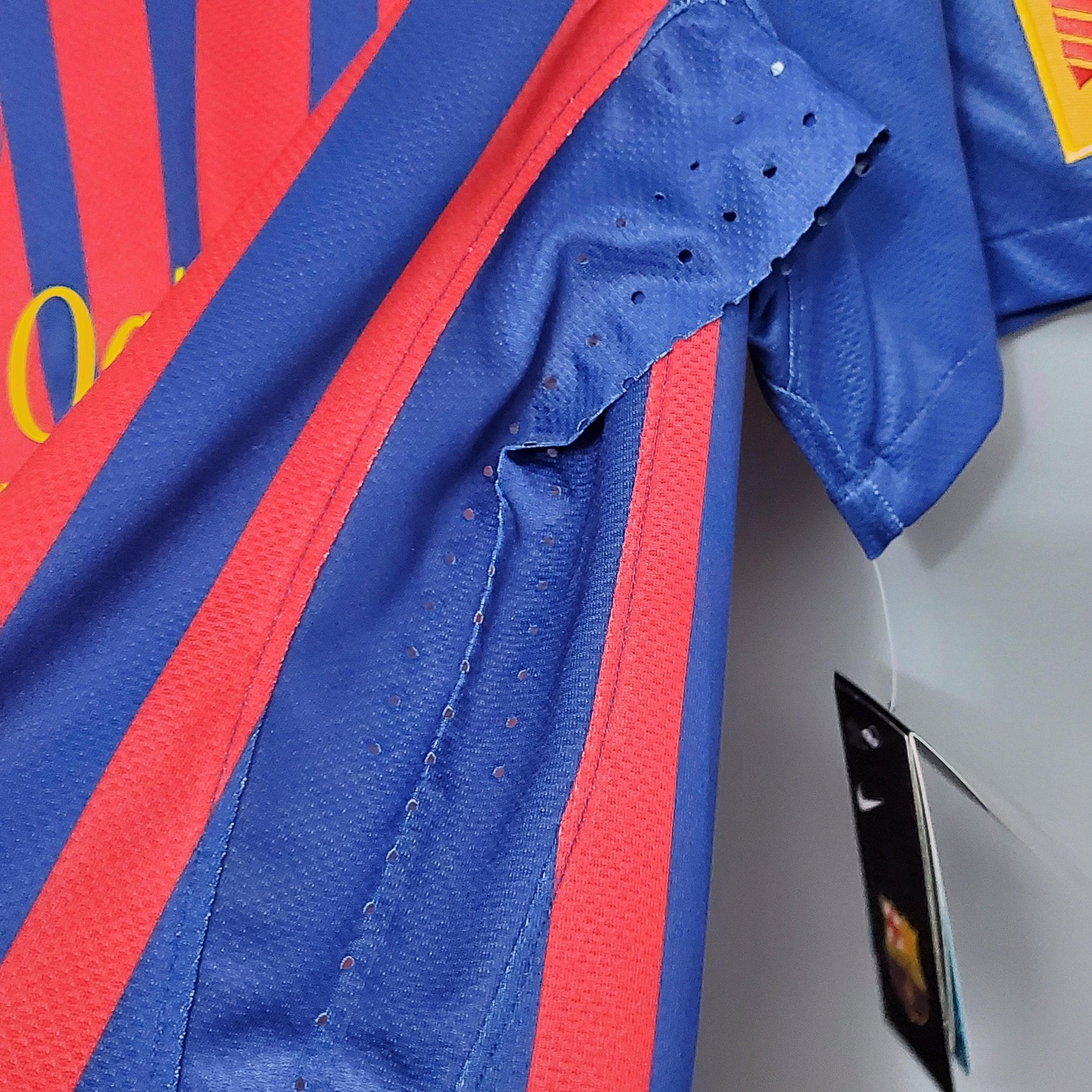 Detalhe da camisa Barcelona Home 11/12 Retro com cores azul e vermelho, mostrando a textura do tecido e a etiqueta.