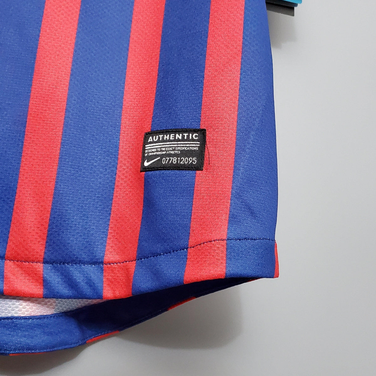 Camisa Barcelona Home 11/12 Retro com detalhes vermelhos e azuis, mostrando a etiqueta Nike e estilo autêntico.