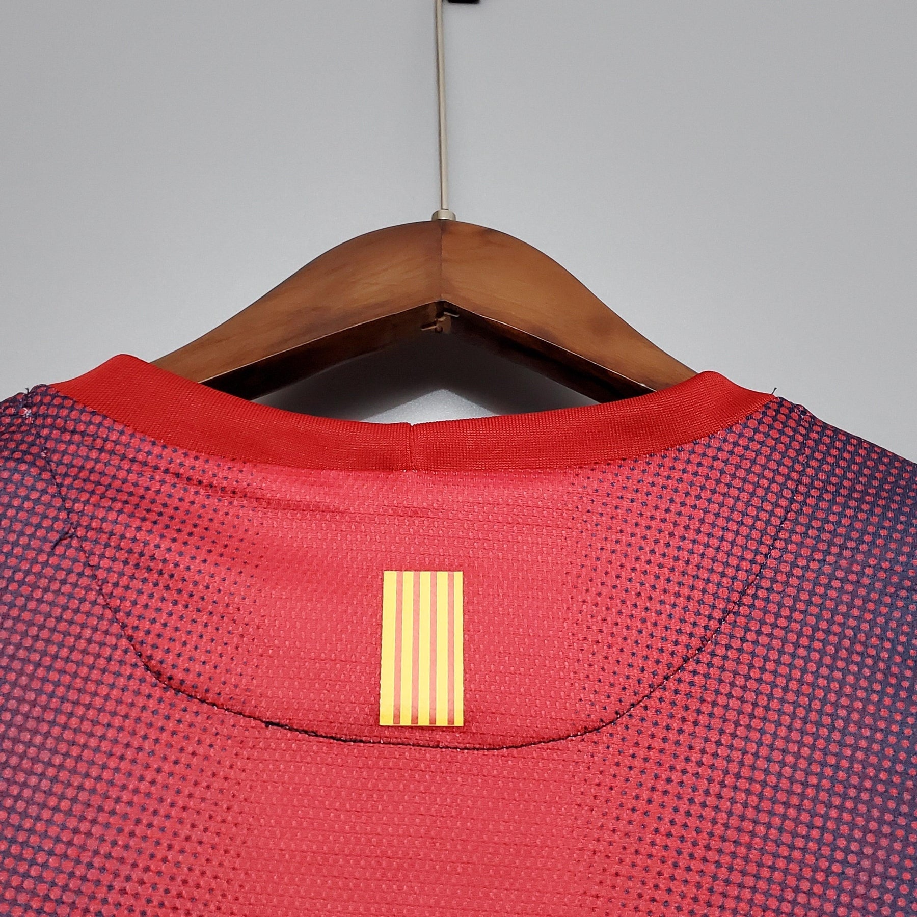 Detalhe da parte de trás da camisa retro Barcelona Home 12/13 com gola vermelha e listras douradas.