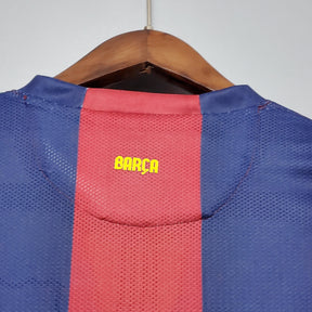 Camisa do Barcelona com detalhe em amarelo nas costas, mostrando a palavra BARÇA na parte de trás.