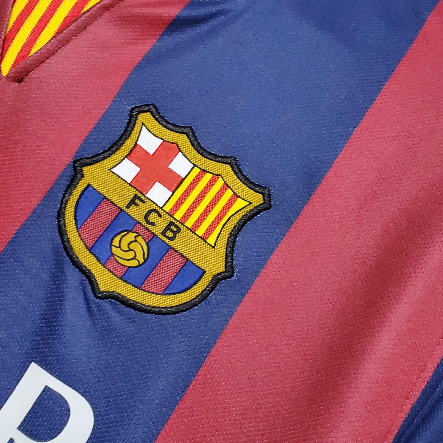 Logo do Barcelona em camisa retro 14/15 disponível na loja olímpica, representando a rica história do clube.