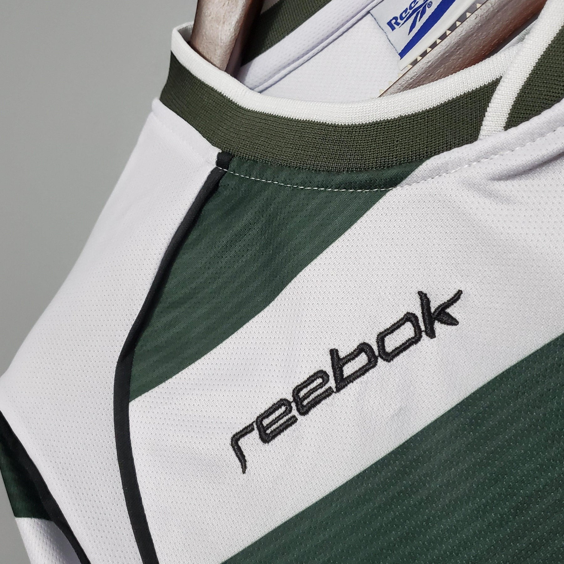 Detalhe da camisola Sporting Lisboa Home 01/03 Retro da OLYMPIC STORE, com logo Reebok em destaque.