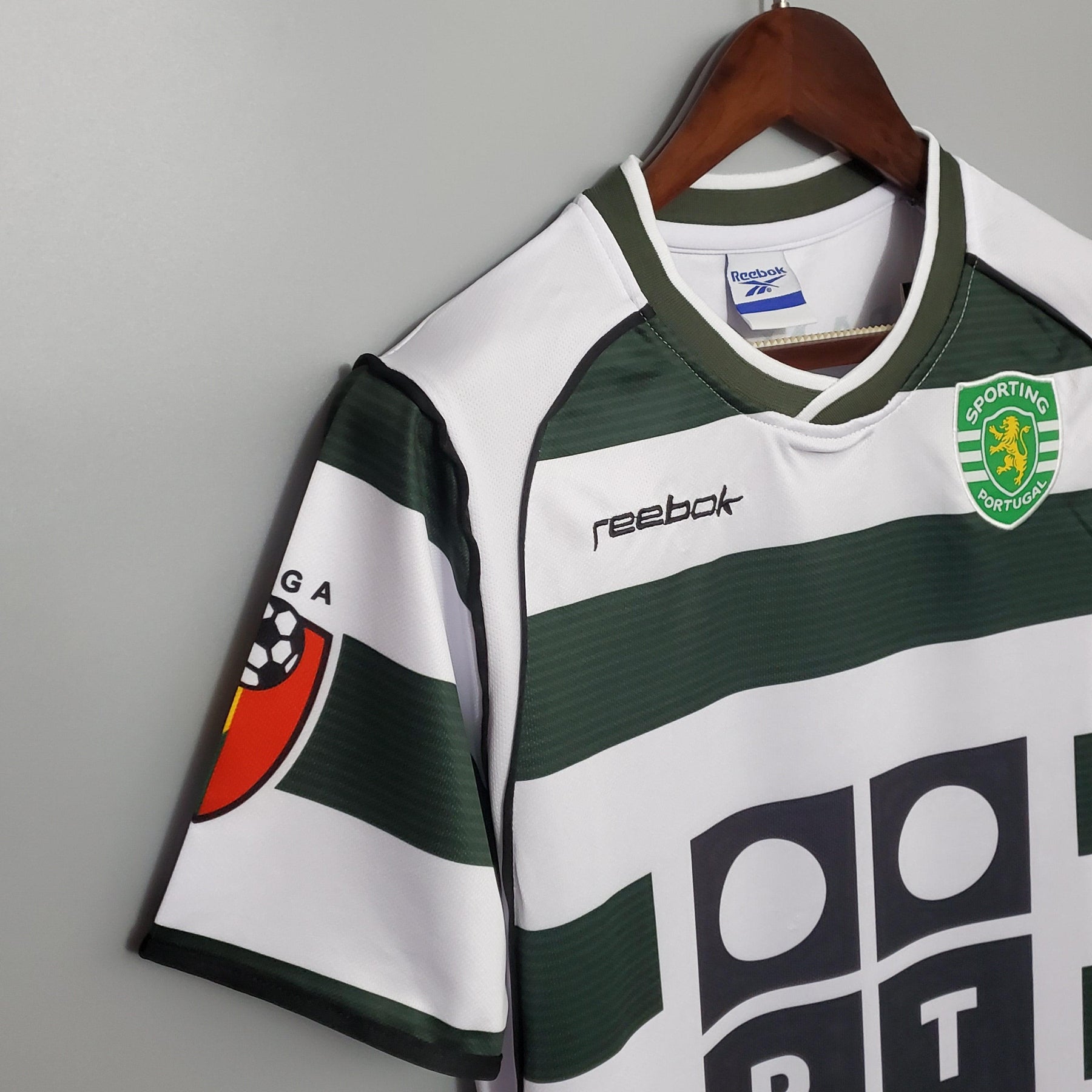 Camisola Sporting Lisboa Home 01/03 Retro da Reebok pendurada, destacando o escudo e as listras verdes e brancas.