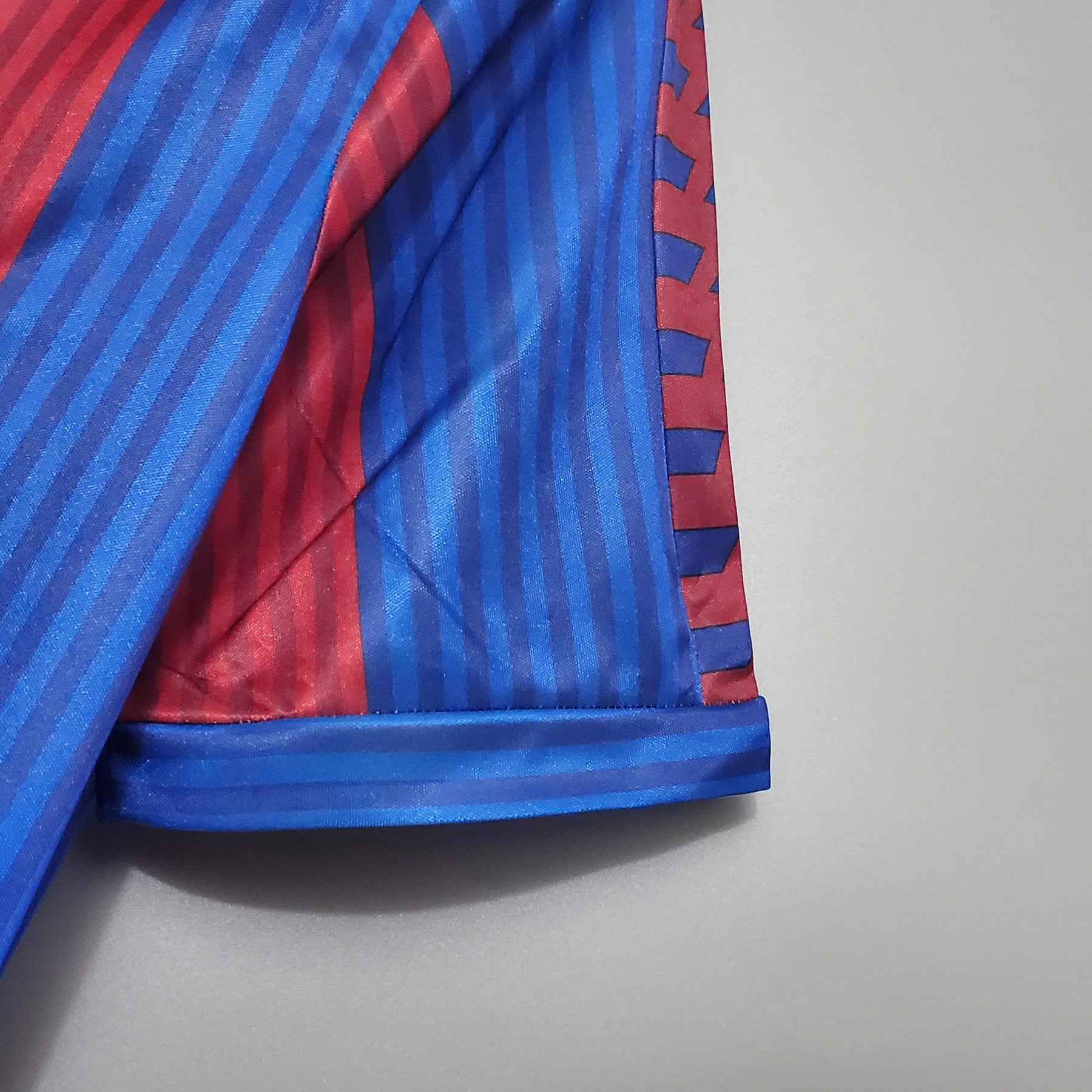 Detalhe da manga da camisa retrô Barcelona 90/91, em azul e vermelho, da loja olímpica.