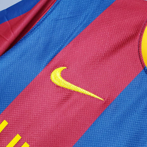 Detalhe do logo Nike na camisa Barcelona Home 10/11 Retro, destacando o design icônico em vermelho e azul.