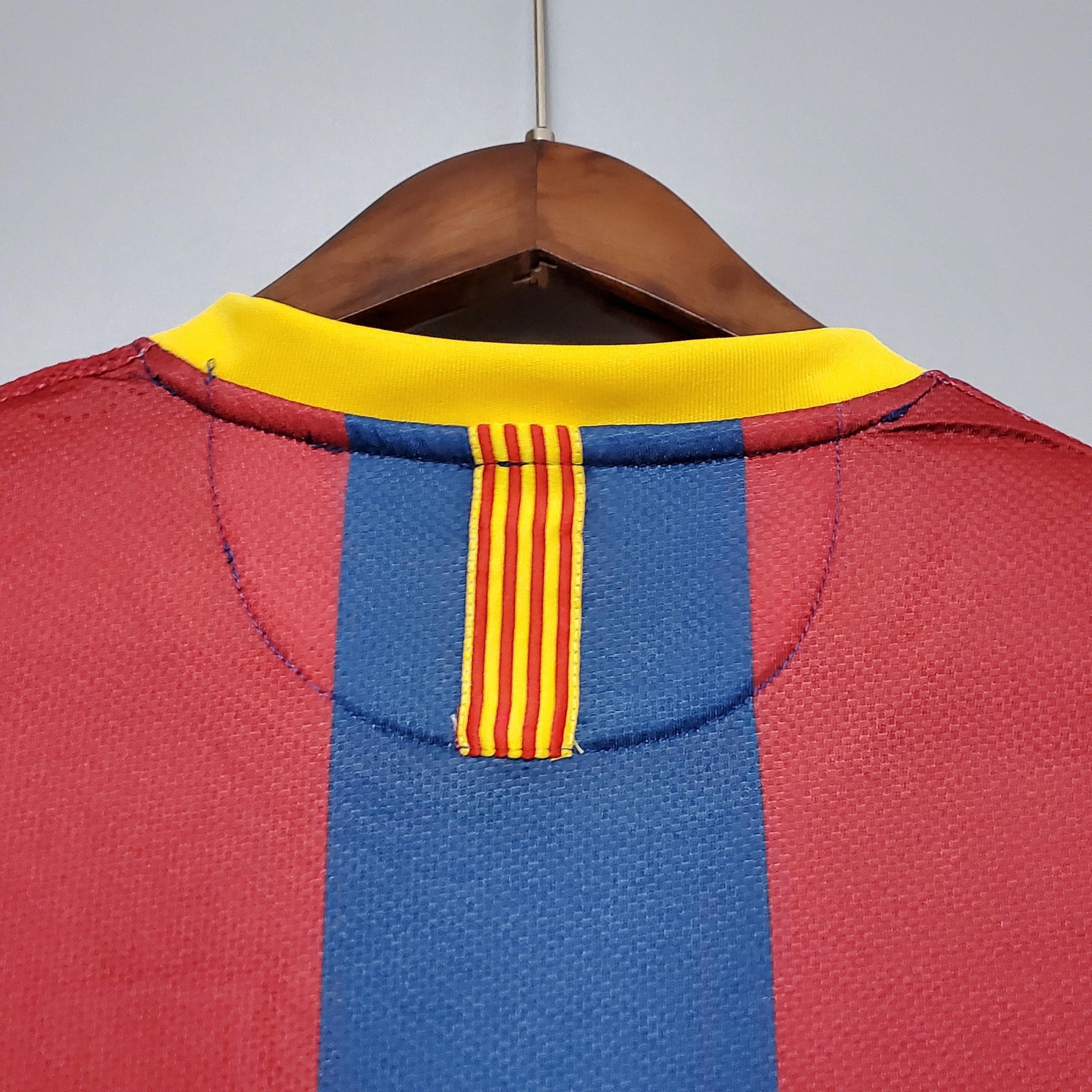 Detalhe da parte de trás da camisa Barcelona Home 10/11 Retro com colo amarelo e listras azul e vermelha.