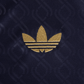 Logotipo dourado da Adidas em fundo azul, destacando o design icônico da marca.