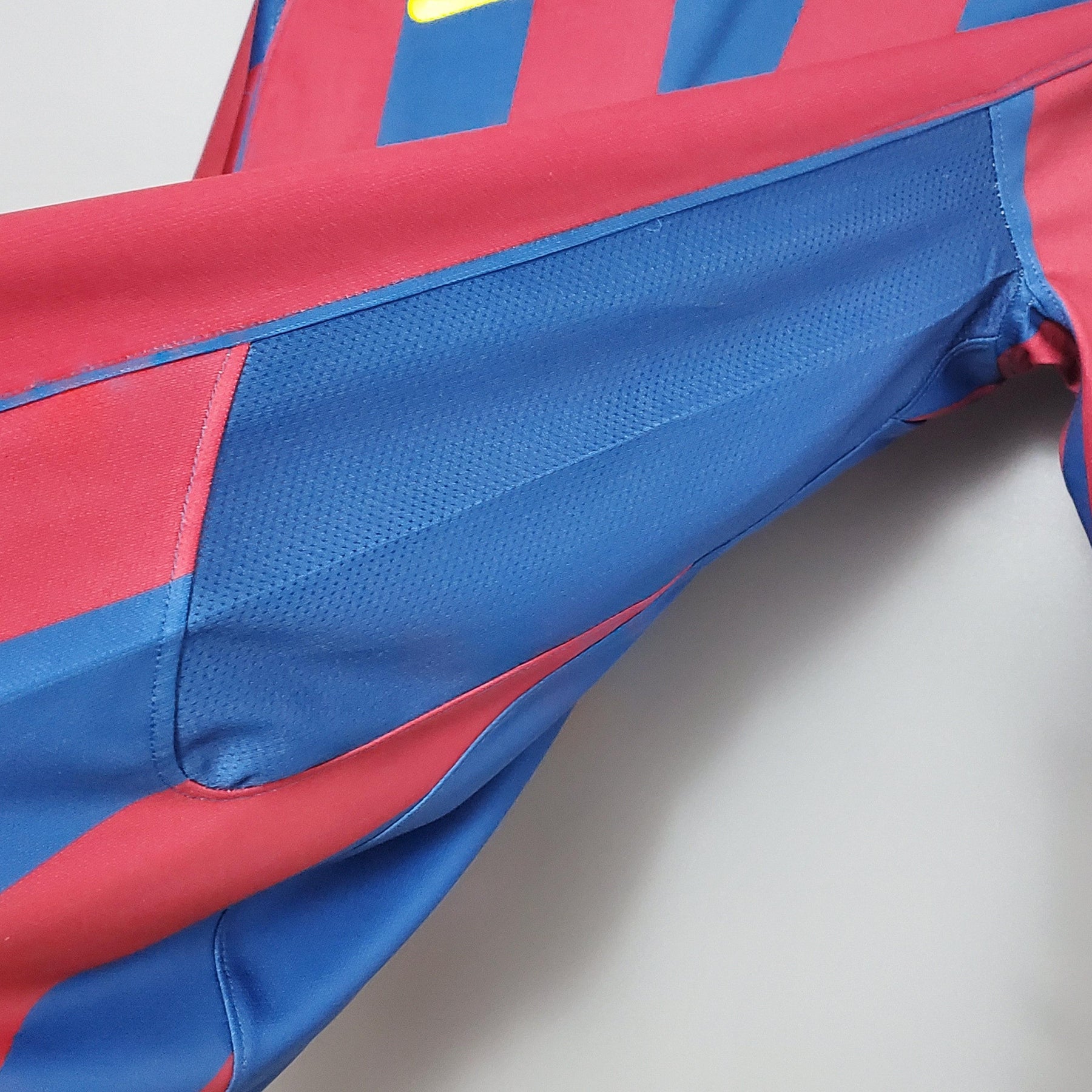 Detalhe da manga da camisa Barcelona Home 2006 Uefa Retro, com cores azul e vermelha vibrantes.