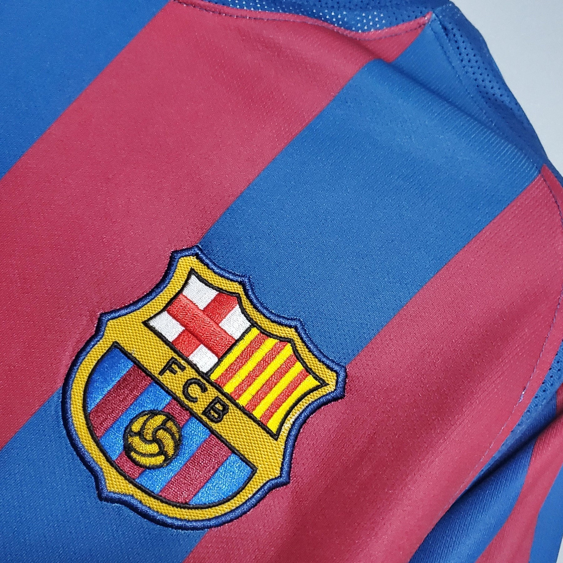Emblema do Barcelona Home 2006 Uefa Retro em camisa, destacando as cores tradicionais do time.