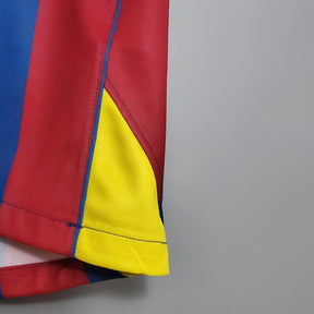 Barcelona Home 2006 UEFA Retro com detalhes em vermelho, azul e amarelo na parte inferior da camiseta.