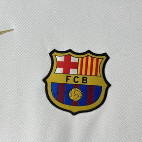 Emblema do FC Barcelona em camisola especial 25/26 com detalhes em azul e vermelho.