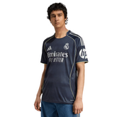 Camisola Real Madrid Away 2025/26 em fundo neutro, modelo masculino com escudo do time e detalhes em azul.