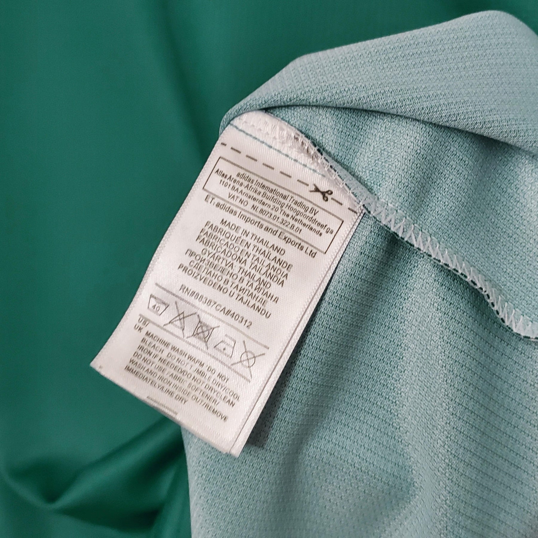 Etiqueta de cuidados da camisola Alemanha Away 1994 Retro, em tecido detalhado, destacando instruções de lavagem.