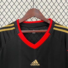 Camisola Alemanha Away 2010 Retro, modelo preto com detalhes em vermelho e dourado, ideal para fãs do futebol.