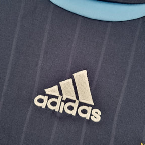 Detalhe do logotipo adidas em uma camisola Argentina Away 06/07 Retro, destacando a qualidade e o design icônico.