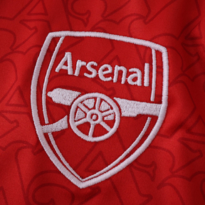 Emblema da Camisola Arsenal Home 2025/26, símbolo do clube em bordado branco sobre fundo vermelho.