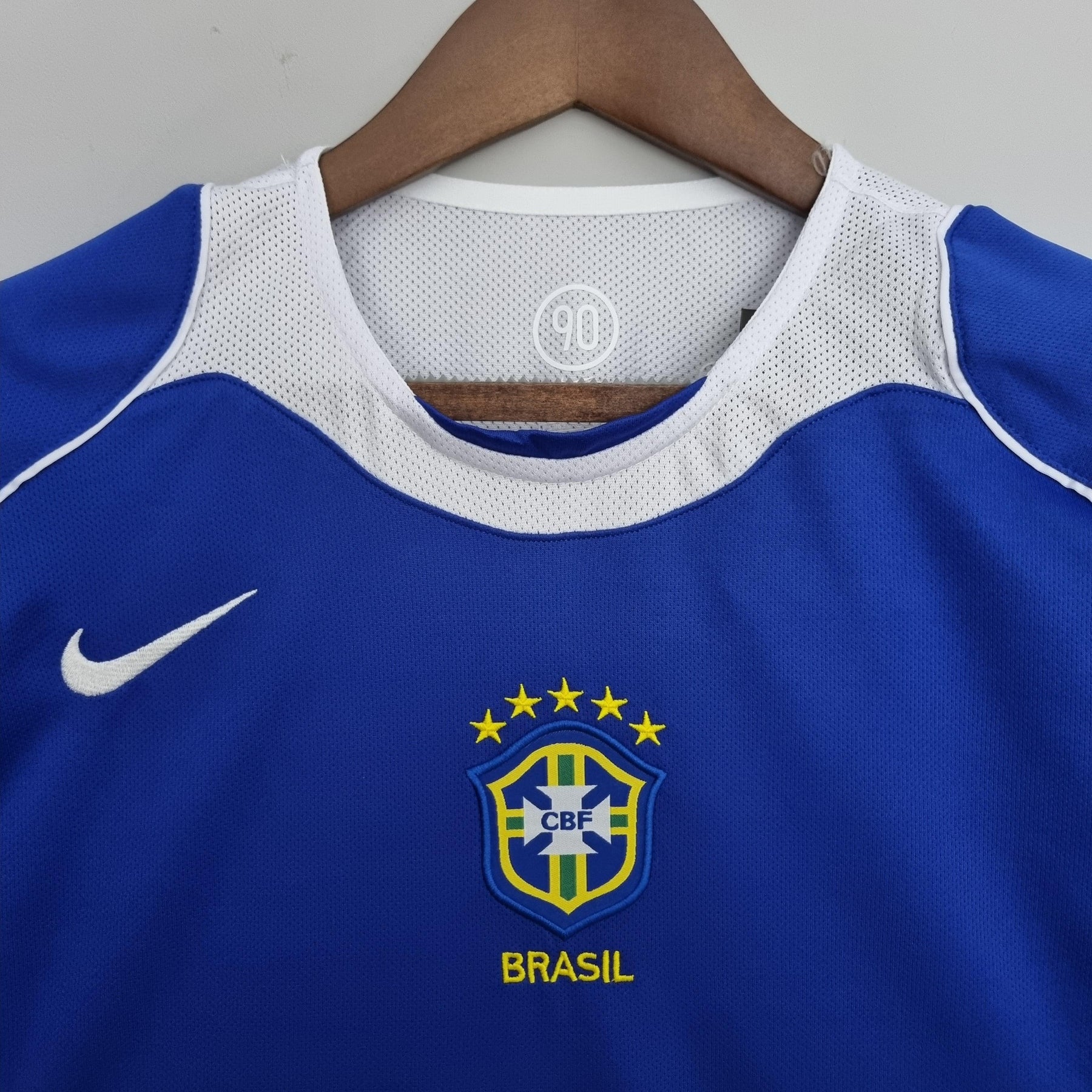 Camisola Brasil Away 04/06 Retro em azul com logo da CBF, destacando o nome Brasil e detalhes em amarelo.