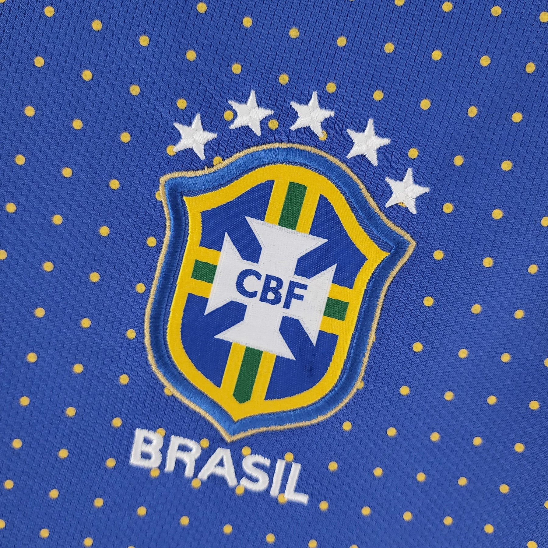 Emblema da Camisola Brasil Away 2010 Retro com estrelas e CBF, destacando a identidade da seleção brasileira.