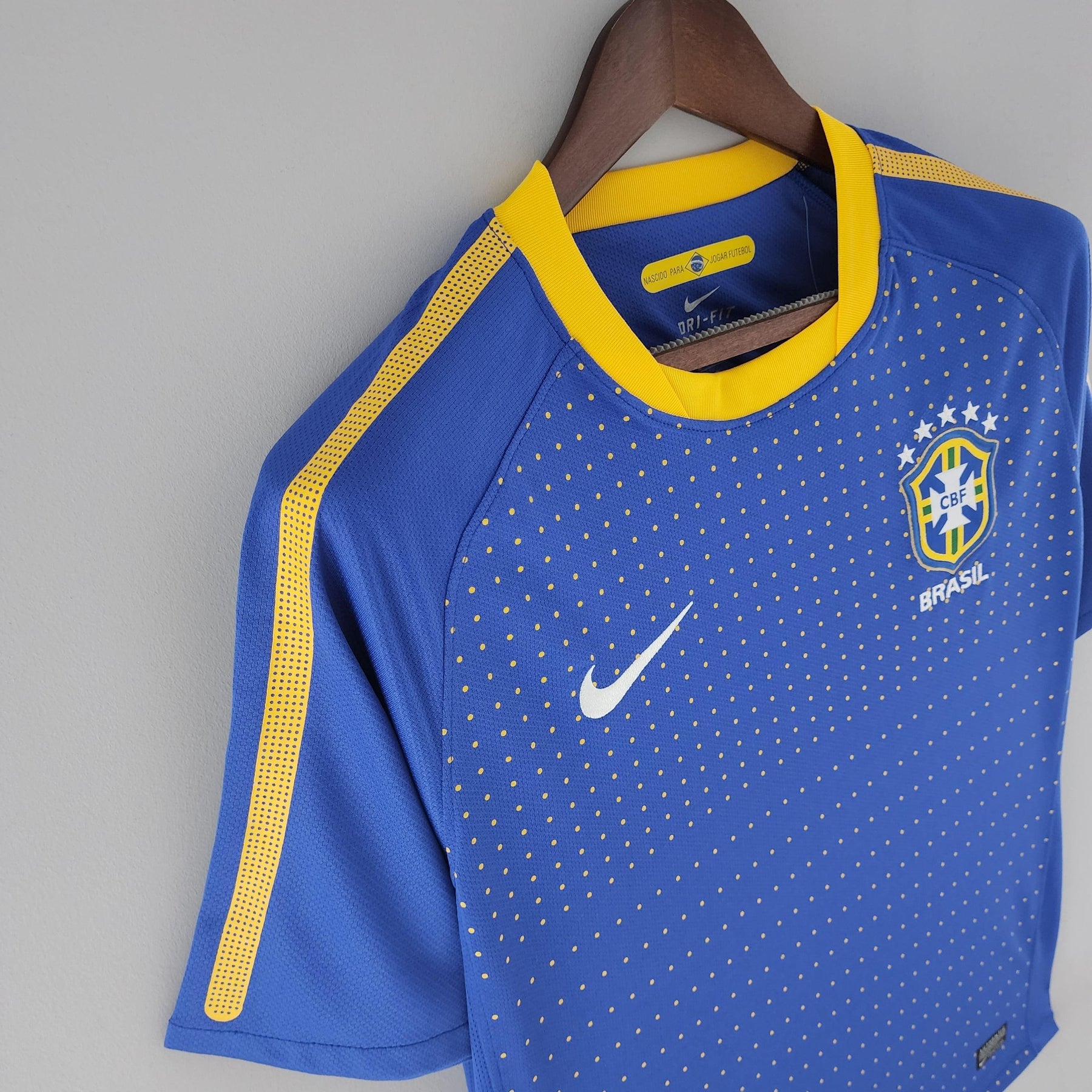 Camisola Brasil Away 2010 Retro em azul com detalhes em amarelo e logo da Nike, destacando a tradição do futebol brasileiro.