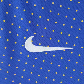 Camisola Brasil Away 2010 Retro com padrão azul e amarelo, logo Nike em destaque. Camisola Brasil para fãs de futebol.