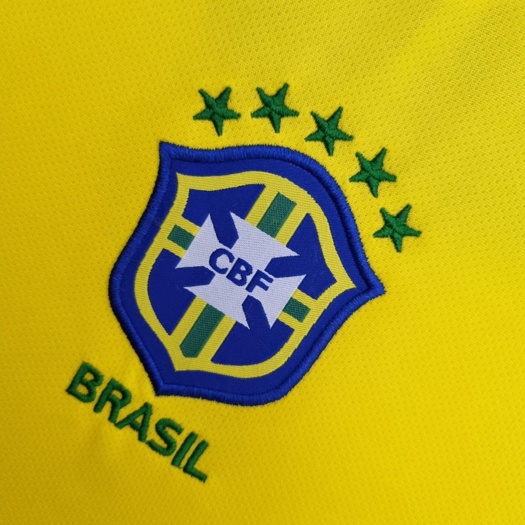 Camisola Brasil Home 04/06 Retro com escudo da CBF e estrelas no fundo amarelo.
