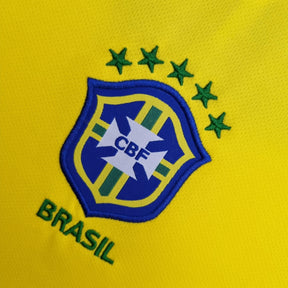 Camisola Brasil Home 04/06 Retro com escudo da CBF e estrelas no fundo amarelo.