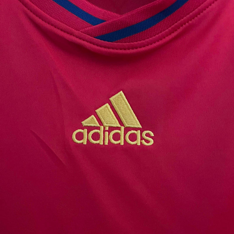 Logotipo adidas em camisola Espanha home 2010 Retro, destacando a cor rosa e detalhes em azul.