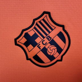 Logotipo da camisola FC Barcelona third laranja 2025/26 - TOTAL 90, destacando o emblema do time.