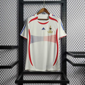 Camisola França 2006 Retro, modelo branco com detalhes em vermelho e azul, disponível na OLYMPIC STORE.