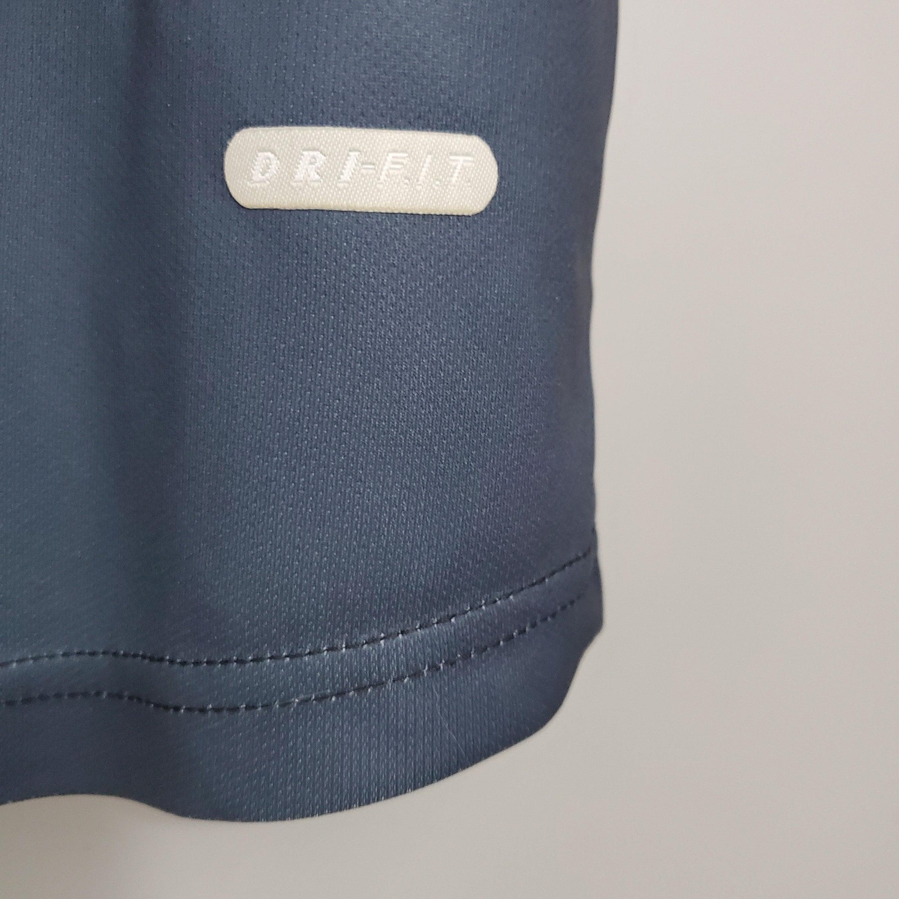 Detalhe da camisa PSG Away 01/02 Retro Azul Olympic, destacando a etiqueta ORI-FIT na parte inferior.