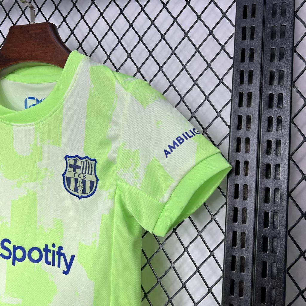 Conjunto Infantil Barcelona third 24/25 em destaque, com logo e detalhes, exibido em fundo de grade.