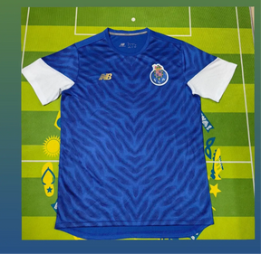 Camisola PRÉ JOGO FC Porto azul 2025/26 com símbolo bordado em fundo verde de campo de futebol.