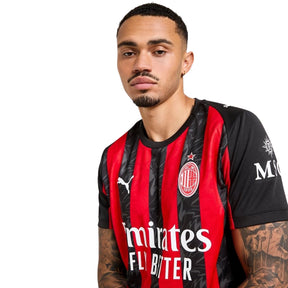Jovem usando a camisola AC Milan Home 2025/26 com design preto e vermelho.