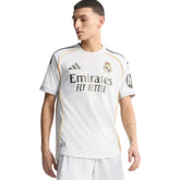 Camisola Real Madrid Home 2025/26, modelo oficial com detalhes em amarelo e logo Emirates, disponível na OLYMPIC STORE.