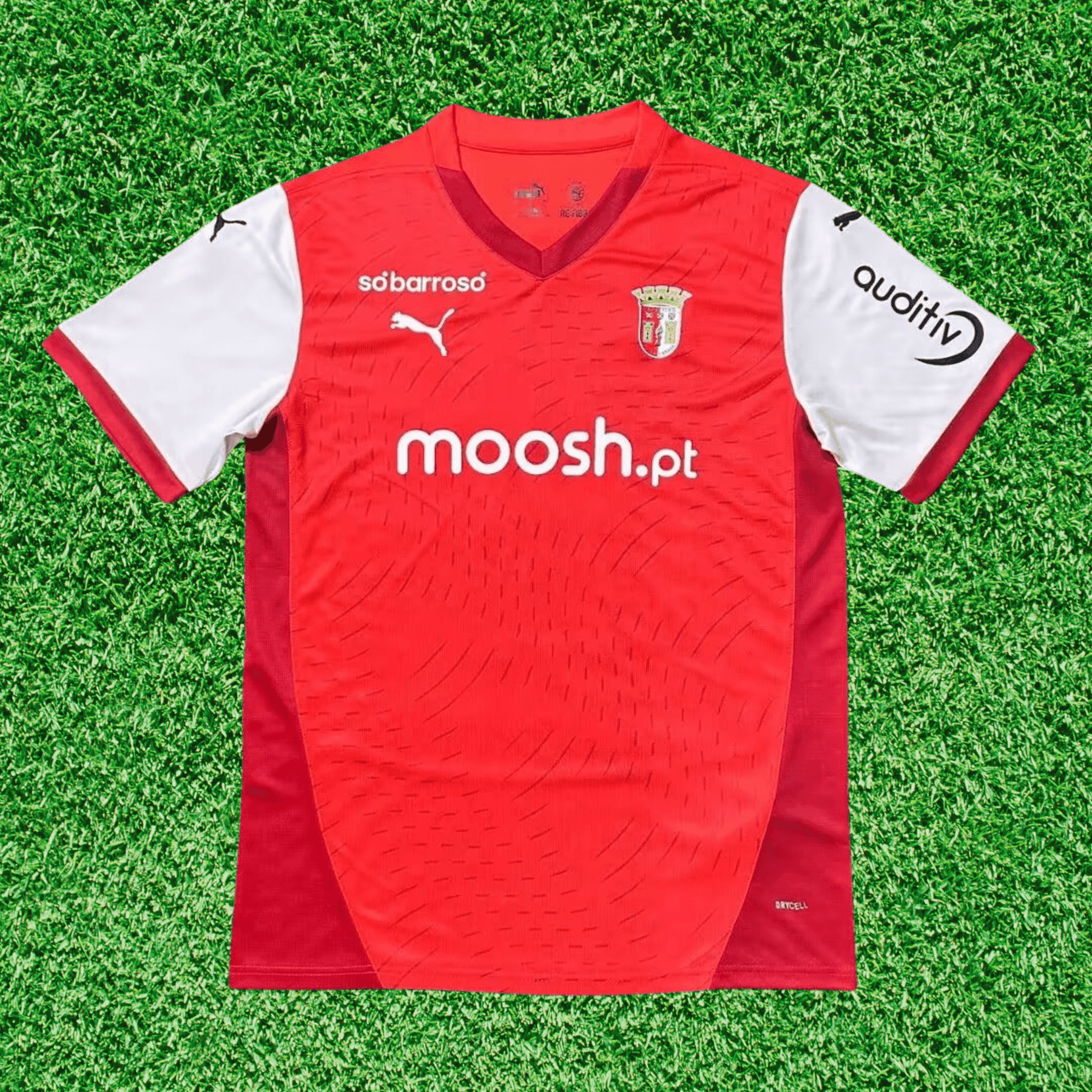 Camisola SC Braga home 24/25 Vermelho na grama, com detalhes em branco e logotipos da Puma e patrocinadores.