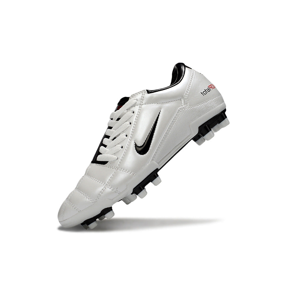 Chuteira Nike Total 90 FG Branca e Preta exibida em ângulo, destacando design e tecnologia para desempenho em campo.