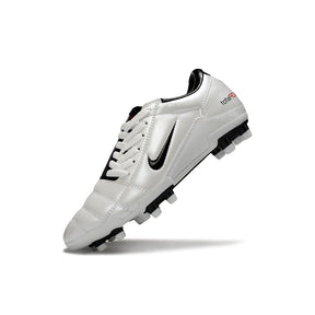 Chuteira Nike Total 90 FG Branca e Preta exibida em ângulo, destacando design e tecnologia para desempenho em campo.