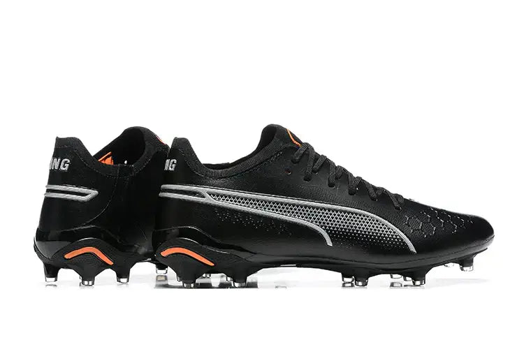 Chuteira Puma King Ultimate FG Preta vista lateral com design elegante e detalhes em laranja.