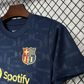 Camisa do Conjunto Infantil Barcelona 24/25 com logotipo do clube e estampa em azul escuro.