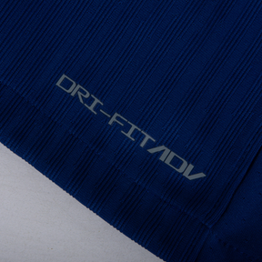 Detalhe da camisa PSG fourth 24/25 - Manga Longa com tecnologia DRI-FIT ADV em fundo azul.