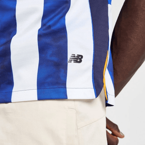 Camisa FC Porto 24/25 em azul e branco, detalhe da logomarca New Balance, vista lateral.