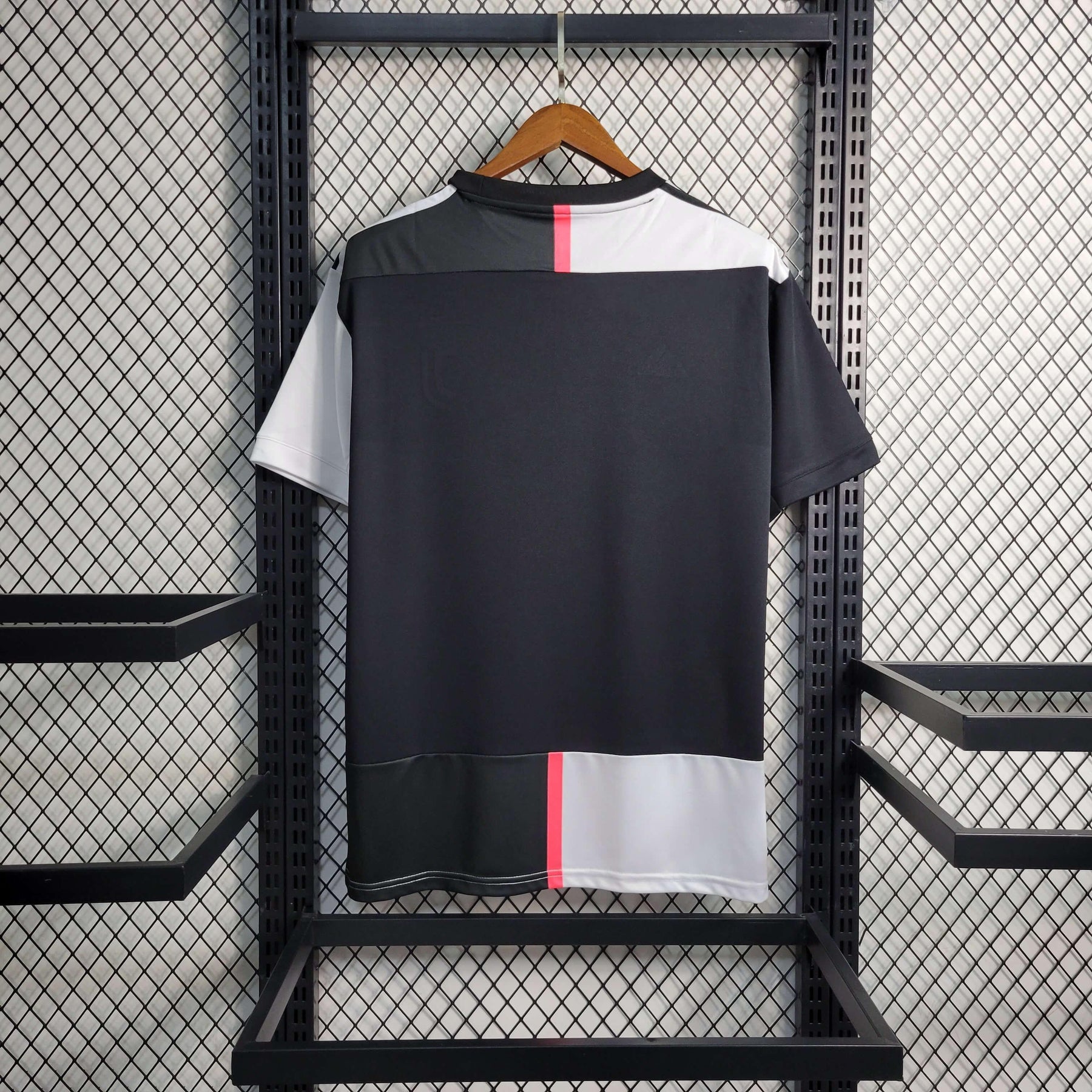 Camisolas Juventus Home 19/20 Retro na cor preta e branca pendurada em um cabide.