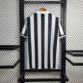 Camisola Juventus Home 98/99 Retro com listras verticais brancas e pretas pendurada em exibição.
