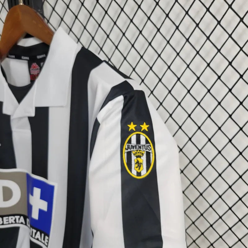 Camisa Juventus Home 98/99 Retro com detalhes em preto e branco e logo da Juventus na manga.